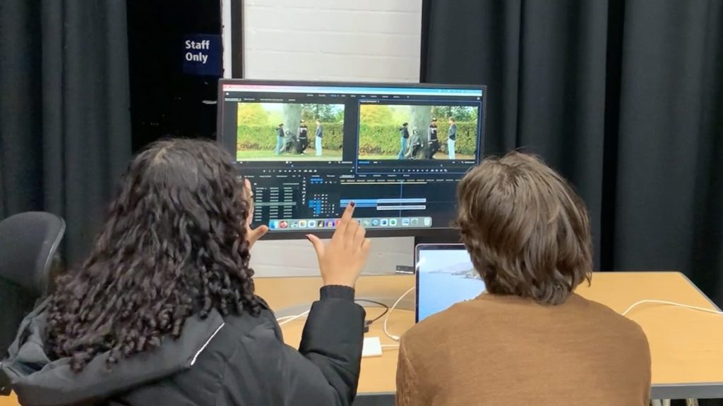 Two young people editing footage together at a computer