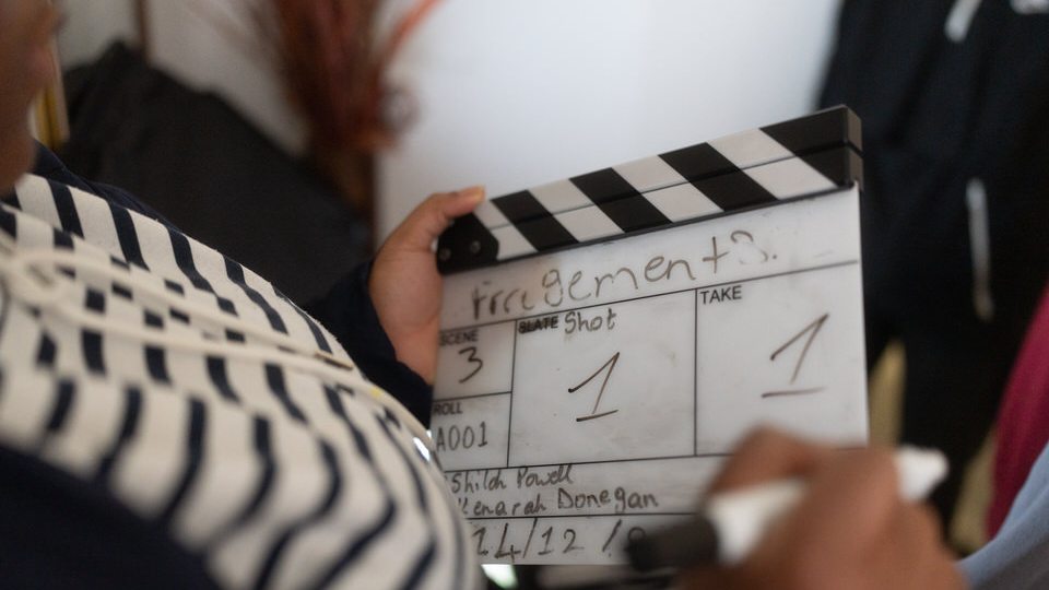 A young person writing the next take on a clapperboard